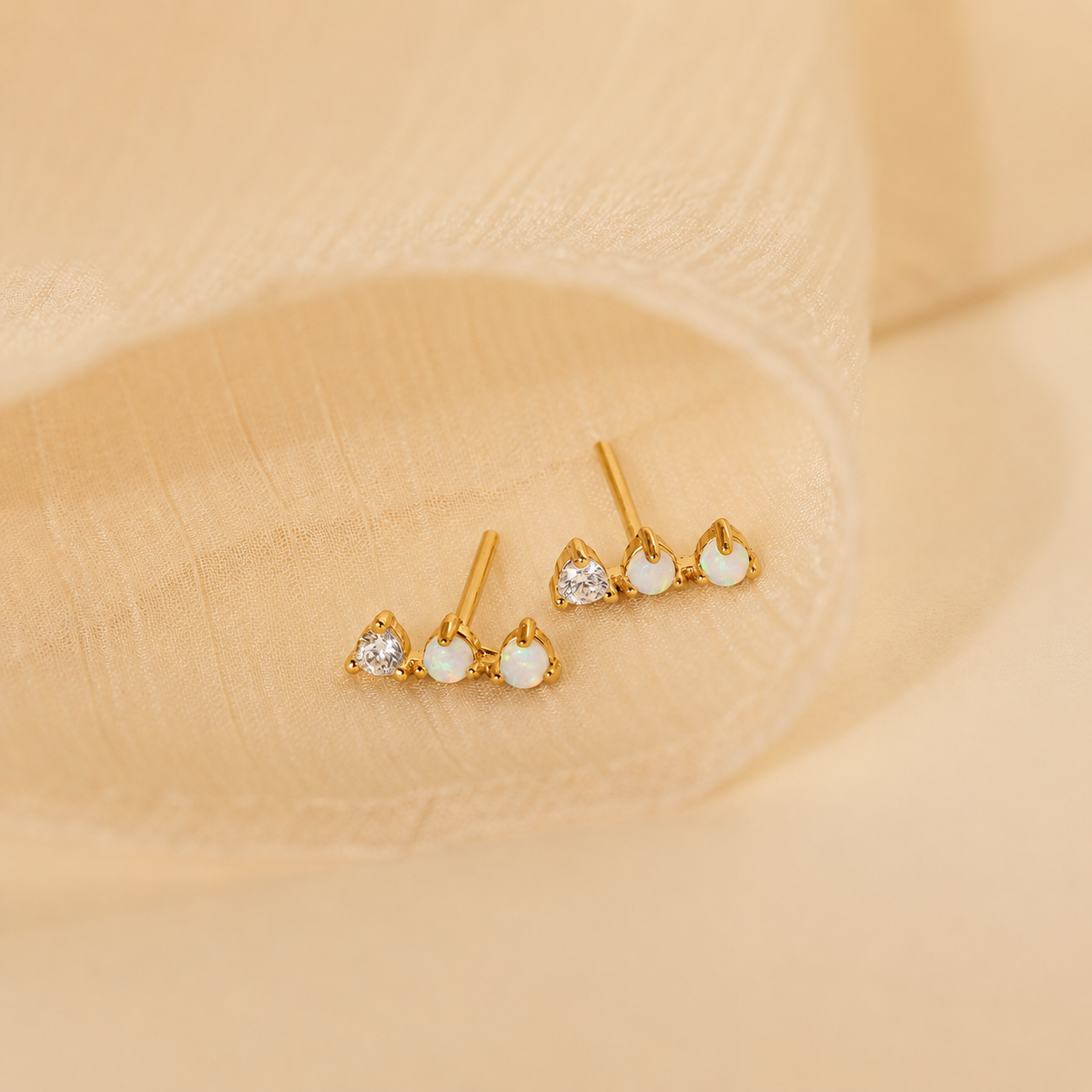Pair of gold earrings with gemstones on a beige background